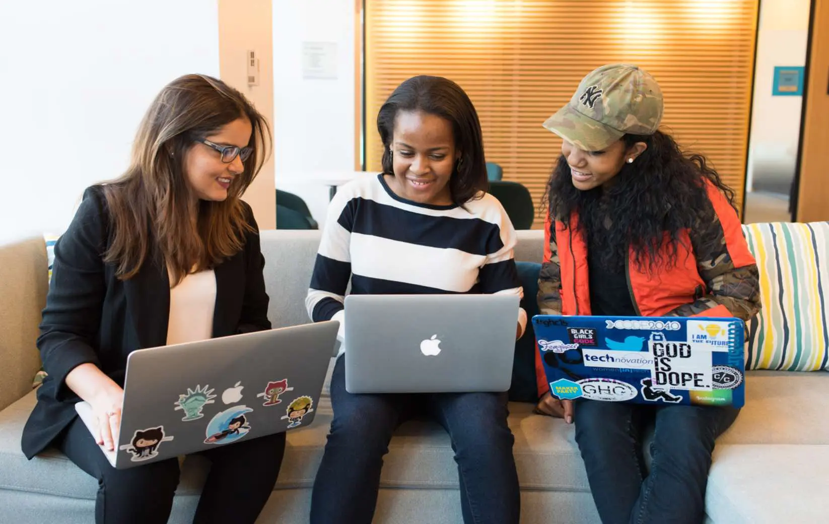 Three individuals engaged in a tutoring session with laptops