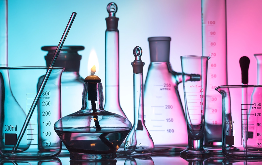 Collection of glass laboratory equipment with a lit candle