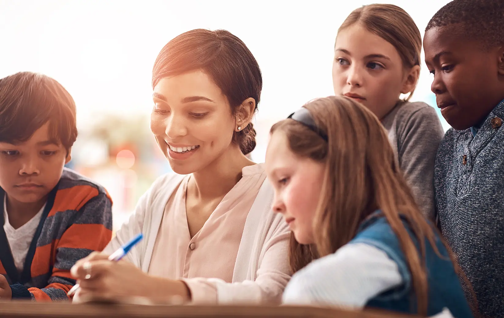 Tutor helping students with their schoolwork in a bright classroom.