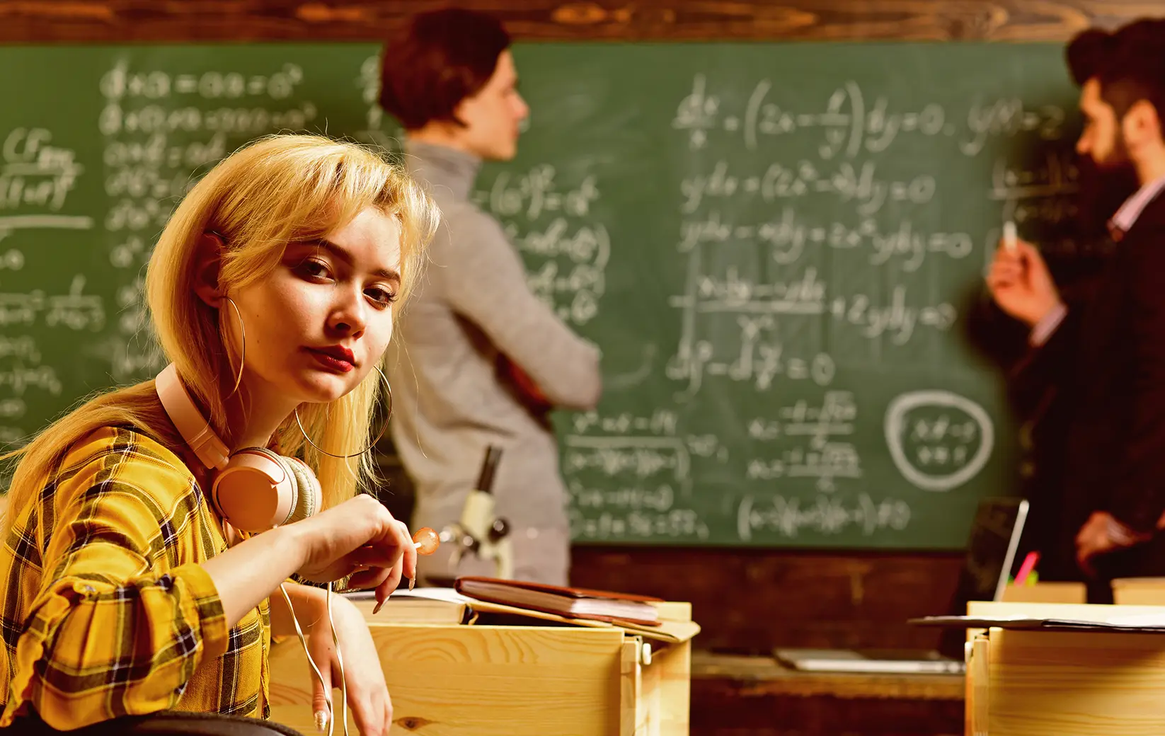 Student with headphones focused on schoolwork in a classroom setting