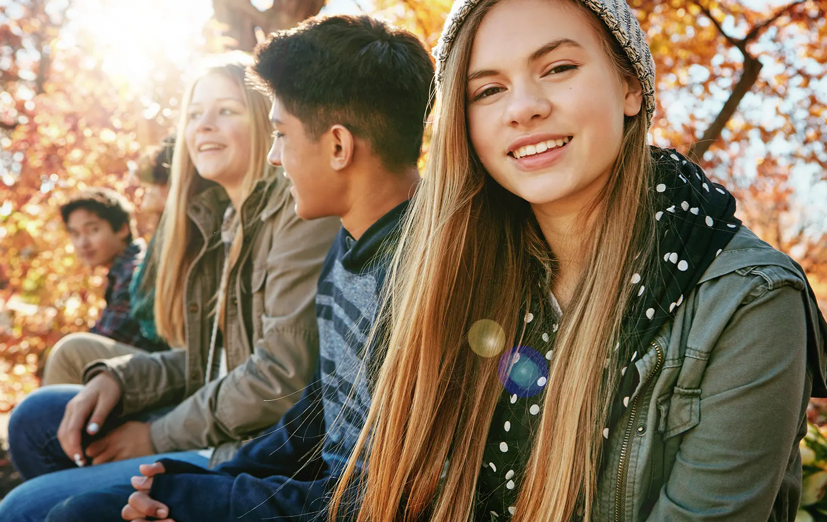 Group of teenagers smiling outdoors in autumn setting
