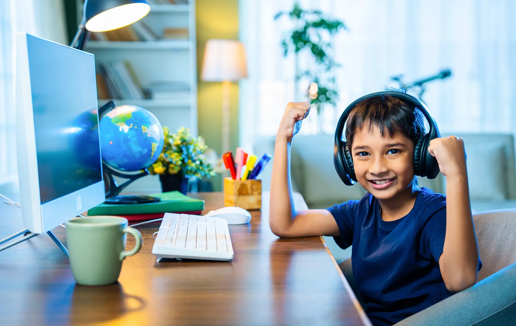Young student wearing headphones, smiling at a computer desk