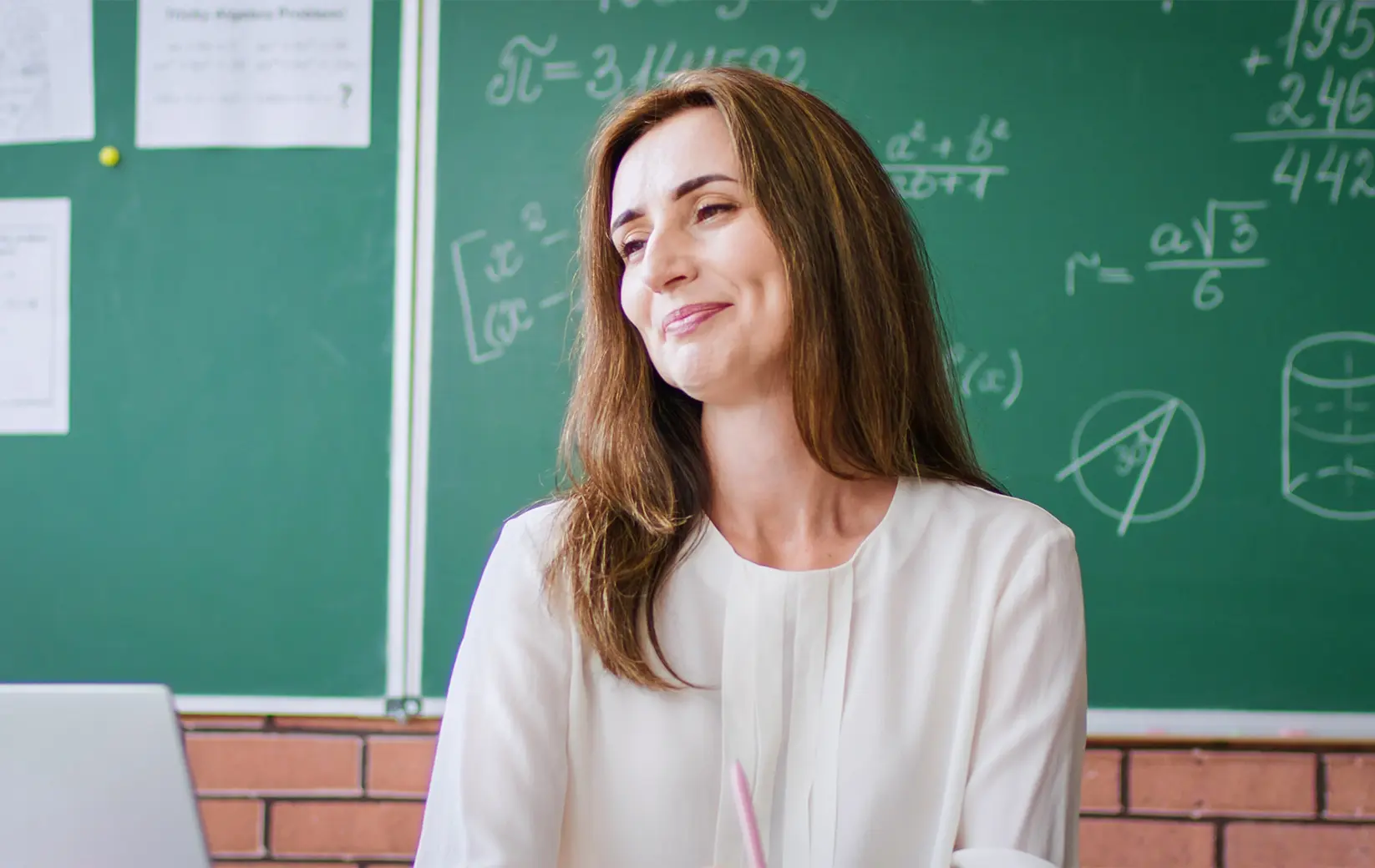Tutor smiling in front of green chalkboard filled with math equations