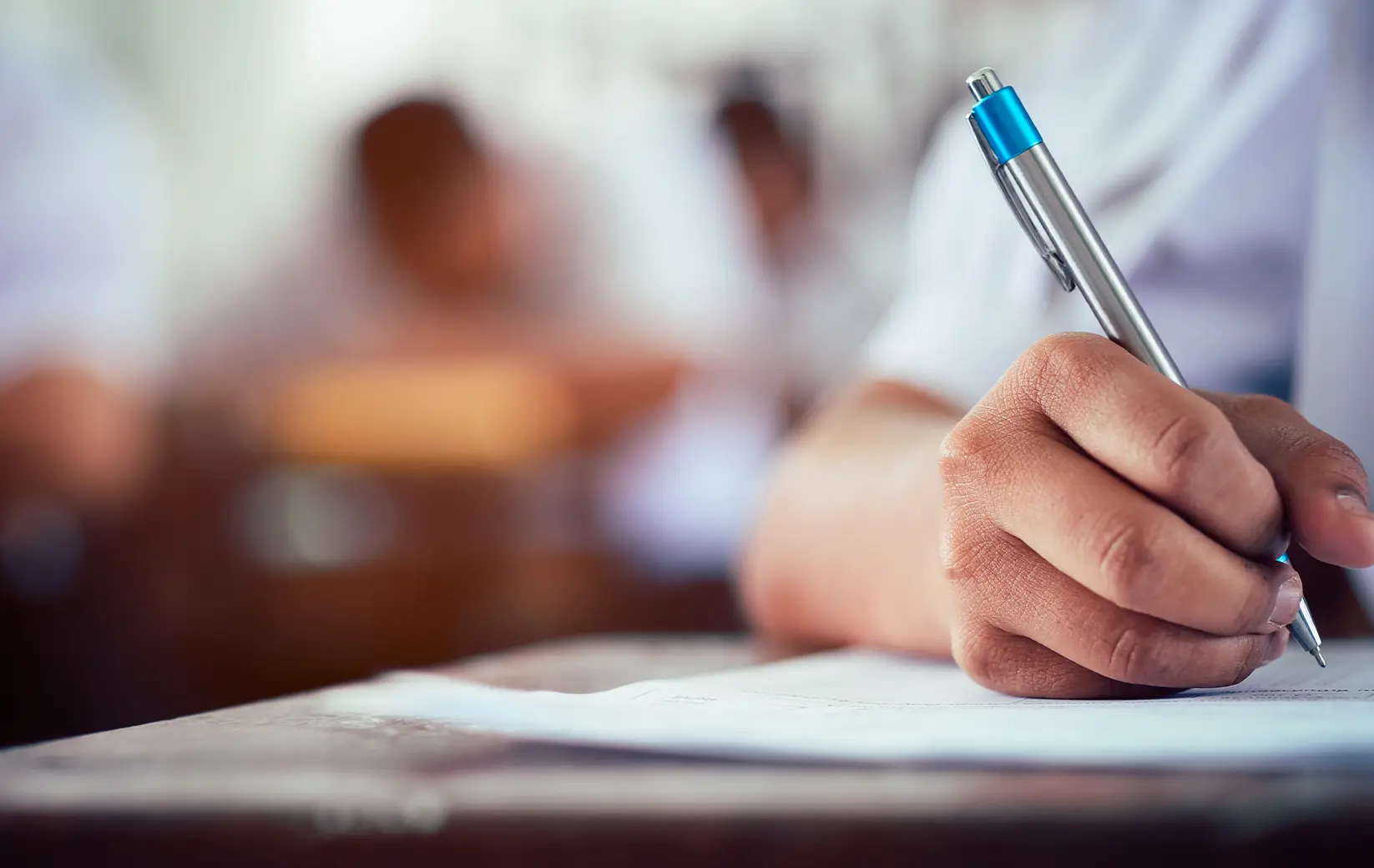 Close-up of a student's hand writing on paper with a pen