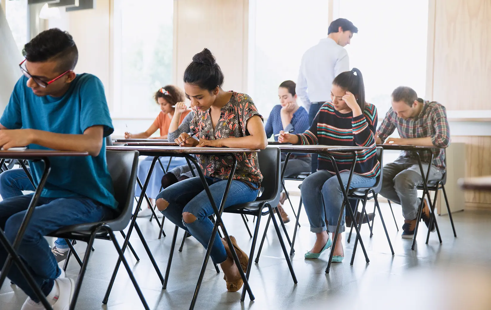 Group of students taking an exam in a classroom setting