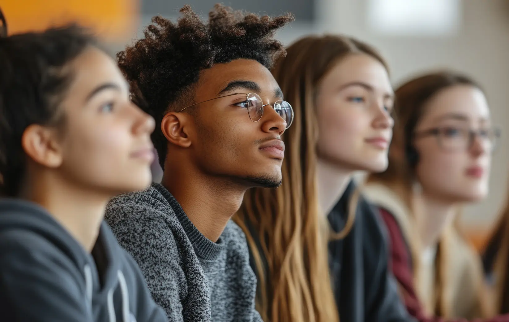 Diverse group of students attentively listening in a classroom.